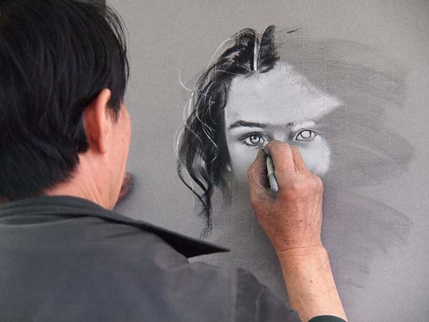 someone drawing a woman's face with chalk